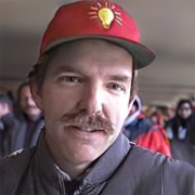 Man with brown hair and mustache wearing a red baseball cap